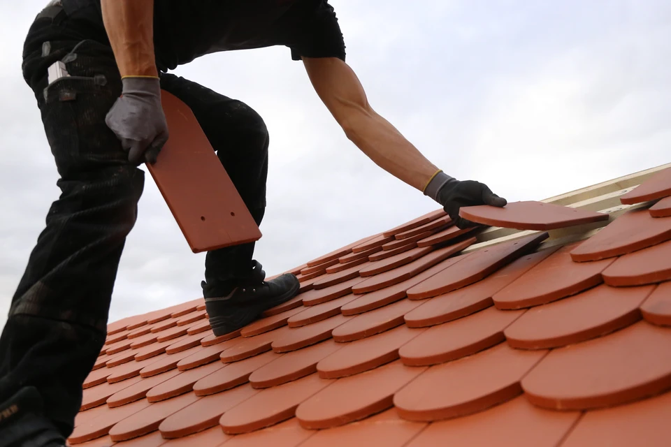 Couvreur professionnel installant des tuiles terre cuite sur toiture en pente