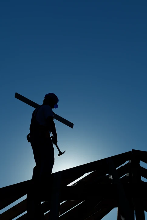 Chantier de construction résidentielle en cours avec ouvriers travaillant sur une maison à deux niveaux